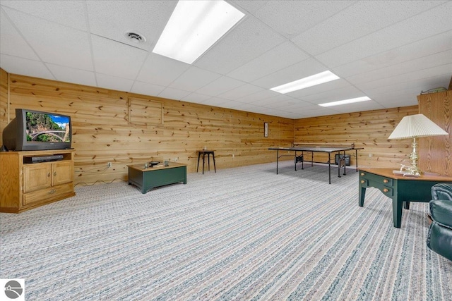 recreation room featuring a drop ceiling, wood walls, and carpet