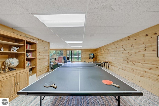 playroom featuring wood walls, a paneled ceiling, and carpet