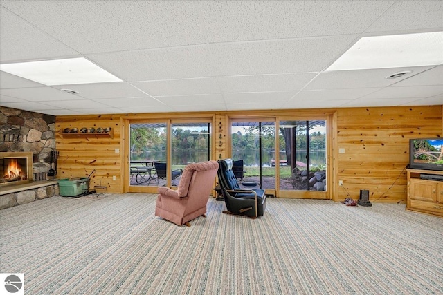 living room featuring wood walls, a drop ceiling, and a wealth of natural light