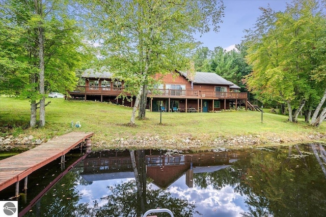 rear view of property with a yard and a deck with water view