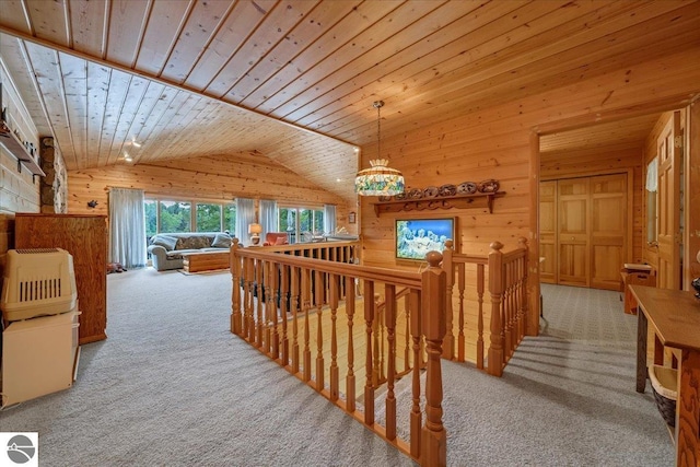 corridor with wood ceiling, light colored carpet, wooden walls, and vaulted ceiling