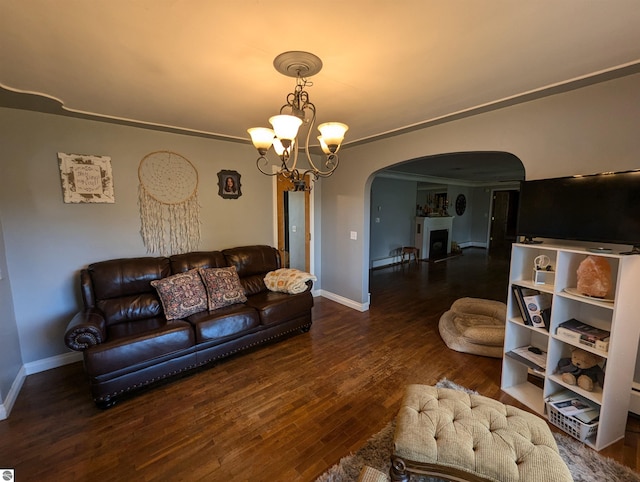 living room featuring an inviting chandelier, crown molding, and dark hardwood / wood-style flooring