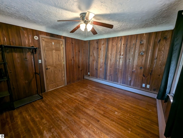 unfurnished bedroom with wooden walls, ceiling fan, and dark hardwood / wood-style floors