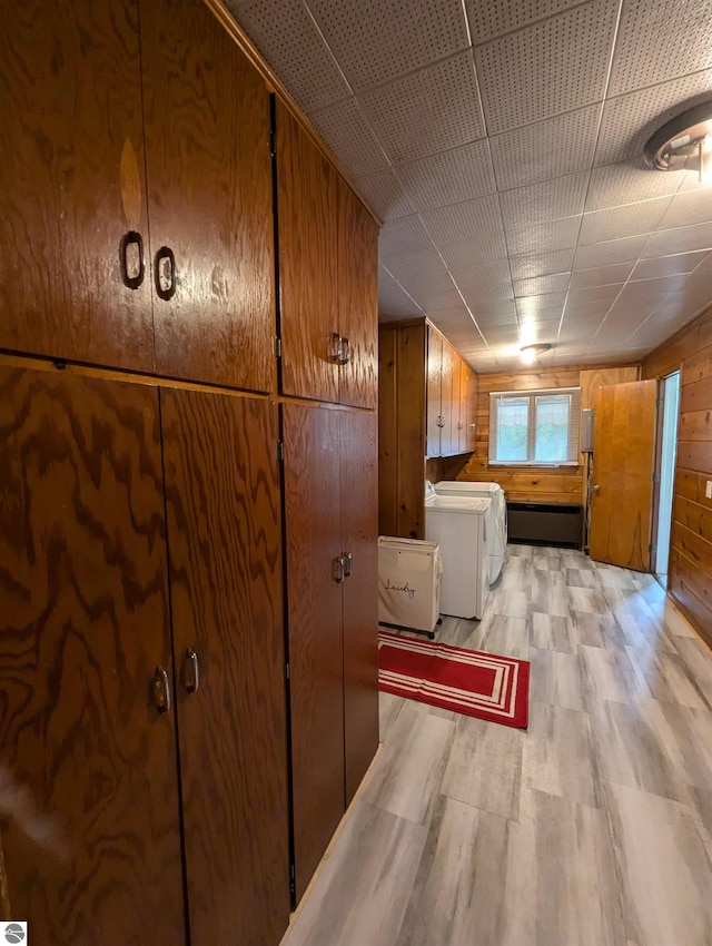 basement featuring washer and clothes dryer, light hardwood / wood-style flooring, wood walls, and a drop ceiling