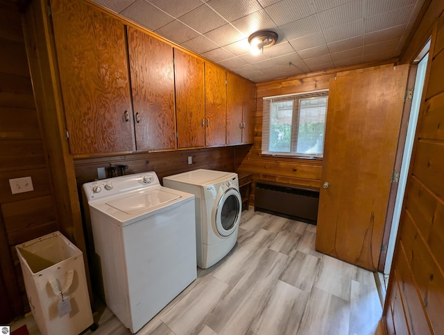 washroom with cabinets, wood walls, light hardwood / wood-style flooring, and washer and clothes dryer