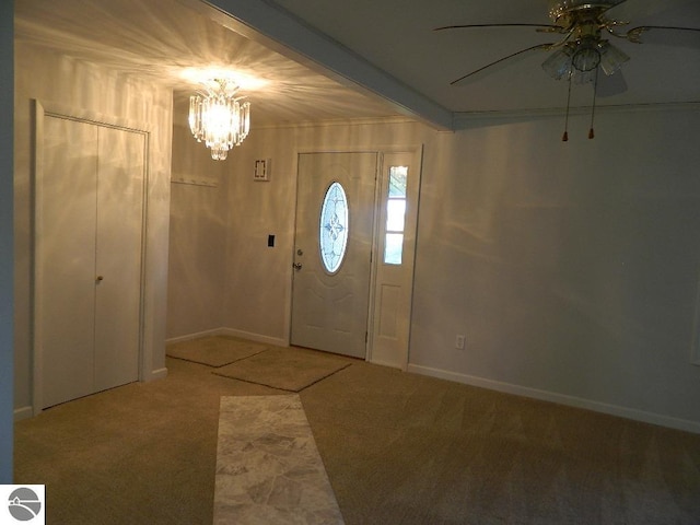 carpeted foyer featuring ornamental molding, ceiling fan with notable chandelier, and beam ceiling