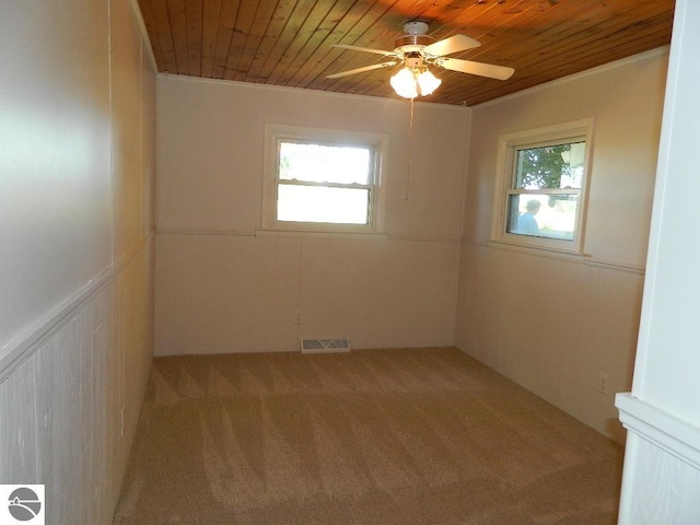 carpeted spare room with wooden ceiling, crown molding, and ceiling fan