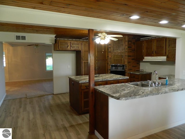 kitchen featuring sink, kitchen peninsula, a kitchen island, ceiling fan, and black oven