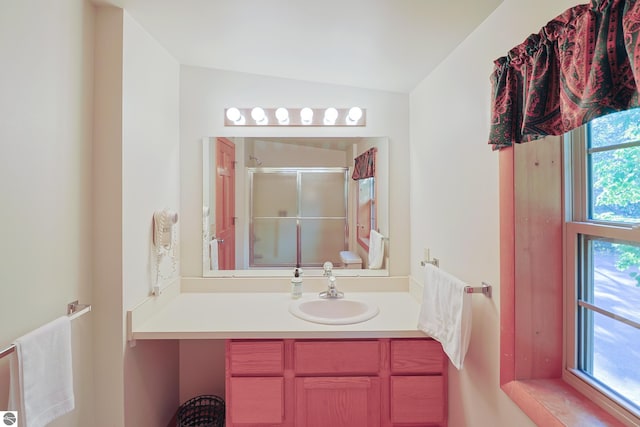 bathroom with vanity, vaulted ceiling, a shower with shower door, and a healthy amount of sunlight