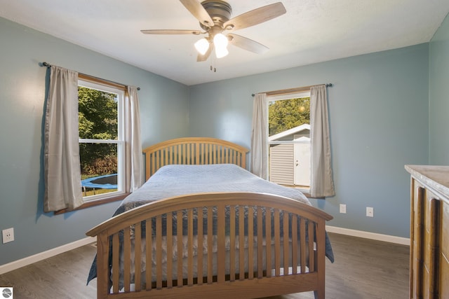 bedroom with ceiling fan, dark wood-type flooring, and multiple windows