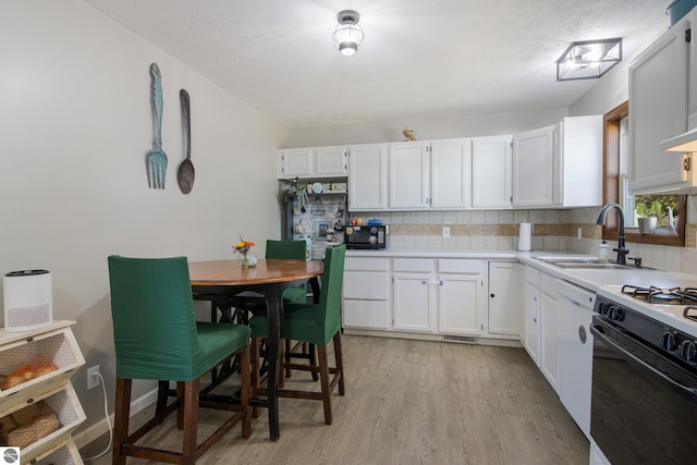 kitchen with light hardwood / wood-style floors, tasteful backsplash, white cabinets, white appliances, and sink