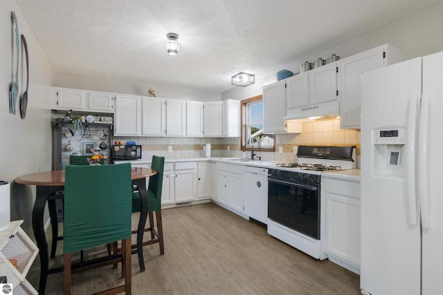 kitchen with tasteful backsplash, white cabinets, white appliances, light wood-type flooring, and a textured ceiling