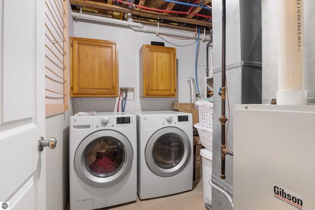 clothes washing area with cabinets, washing machine and dryer, and heating unit