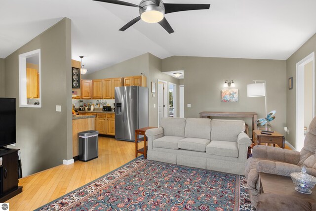 living room featuring ceiling fan, lofted ceiling, and light hardwood / wood-style flooring