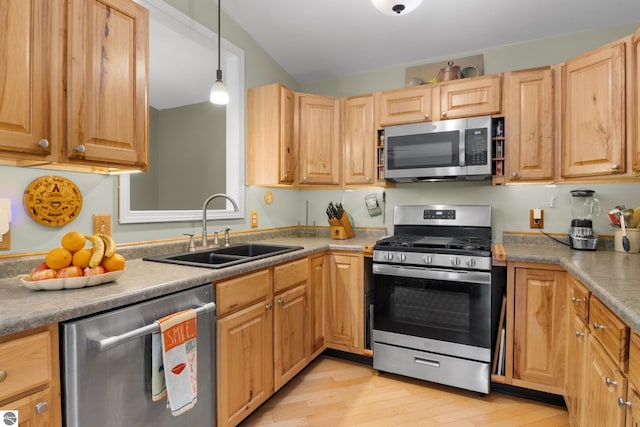 kitchen with lofted ceiling, hanging light fixtures, sink, light hardwood / wood-style flooring, and stainless steel appliances