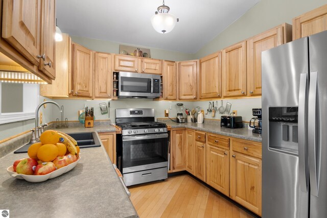 kitchen with light hardwood / wood-style flooring, stainless steel appliances, lofted ceiling, and light brown cabinetry