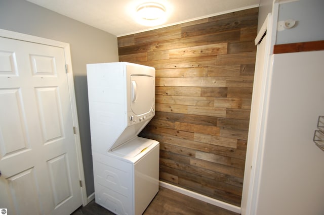 laundry room featuring wood walls and stacked washing maching and dryer