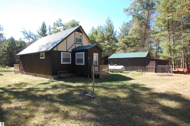 exterior space with a wooden deck, an outbuilding, and a yard