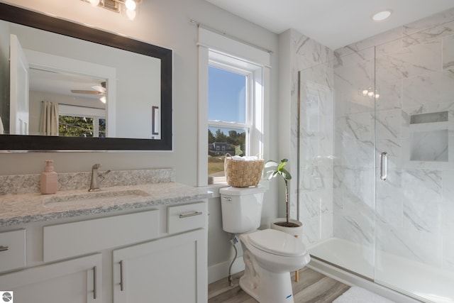 bathroom with vanity, toilet, ceiling fan, a shower with door, and hardwood / wood-style floors