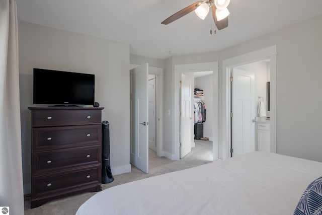 bedroom featuring light carpet, ensuite bathroom, and ceiling fan