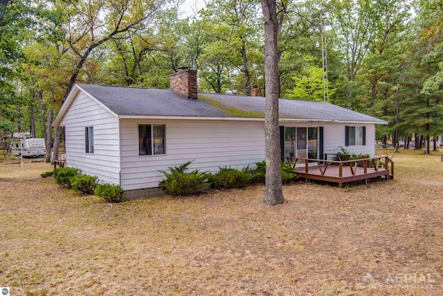 2169 Brady Dr, West Branch, MI 48661 - back of house with a chimney, a deck, a shingled roof, and view of scattered trees
