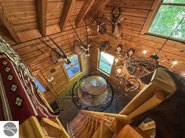 unfurnished living room with wooden walls, beam ceiling, and wooden ceiling