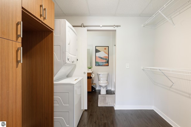 laundry room featuring a barn door, dark hardwood / wood-style floors, and stacked washer / drying machine