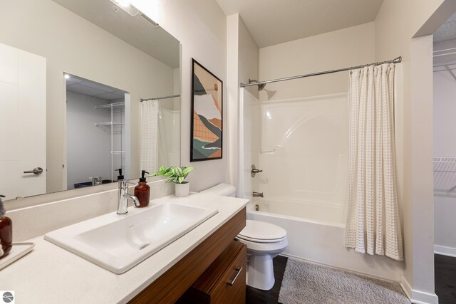 full bathroom with wood-type flooring, shower / bath combination with curtain, vanity, and toilet