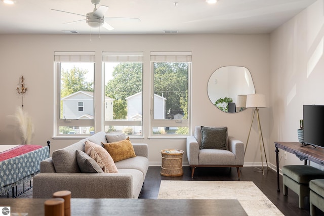 living room featuring ceiling fan, plenty of natural light, and dark wood-type flooring