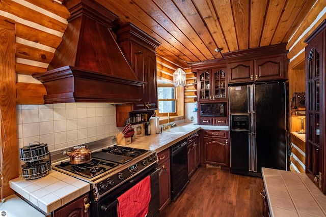 kitchen featuring dark wood-type flooring, custom range hood, black appliances, tile countertops, and wooden ceiling