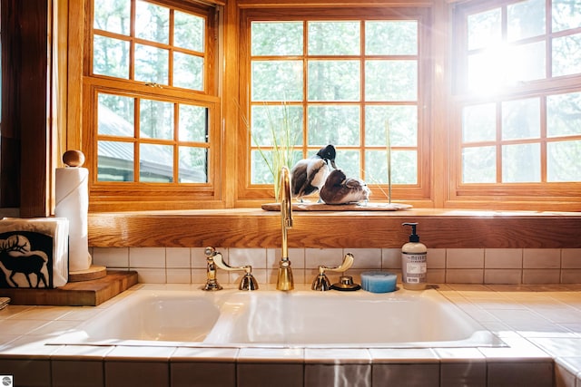 bathroom with a wealth of natural light, tiled bath, and sink