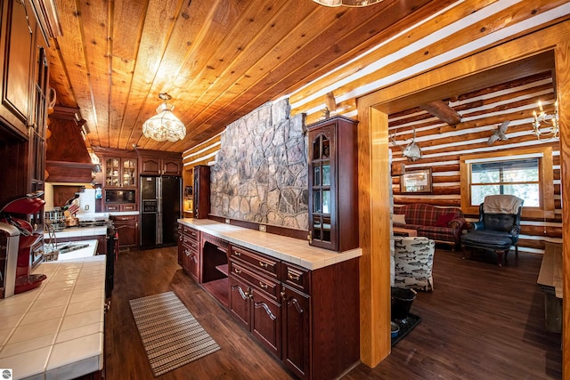 kitchen with black appliances, dark hardwood / wood-style flooring, pendant lighting, and rustic walls