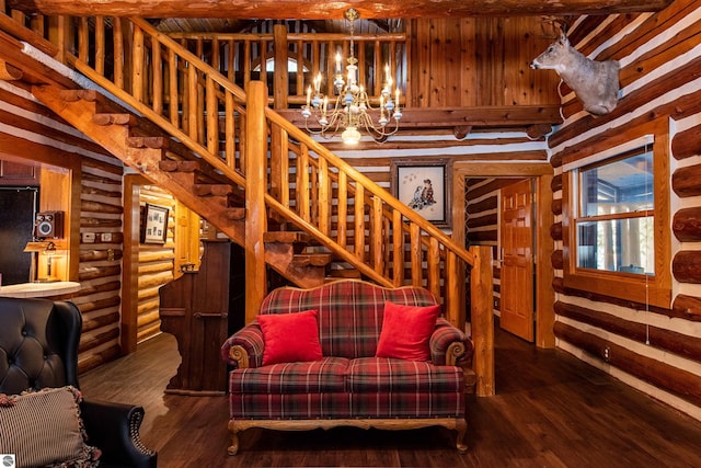 living room featuring wood-type flooring, beamed ceiling, an inviting chandelier, and log walls