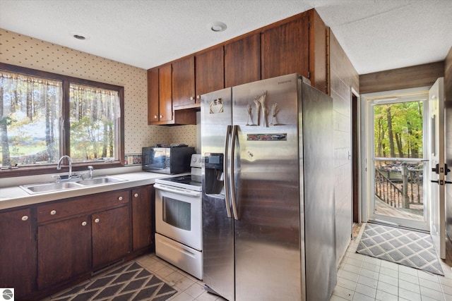 kitchen with a textured ceiling, electric range, light tile patterned flooring, sink, and stainless steel refrigerator with ice dispenser