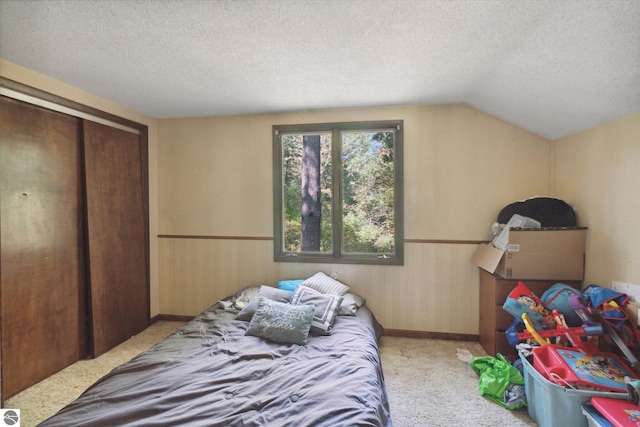 carpeted bedroom featuring a textured ceiling, a closet, and vaulted ceiling