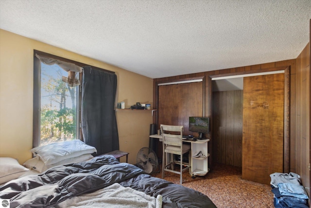 carpeted bedroom with a textured ceiling and wooden walls