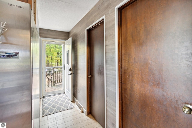 corridor featuring a textured ceiling and light tile patterned flooring