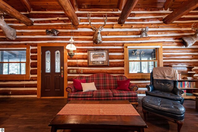 living room with beamed ceiling, log walls, dark wood-type flooring, and a wealth of natural light