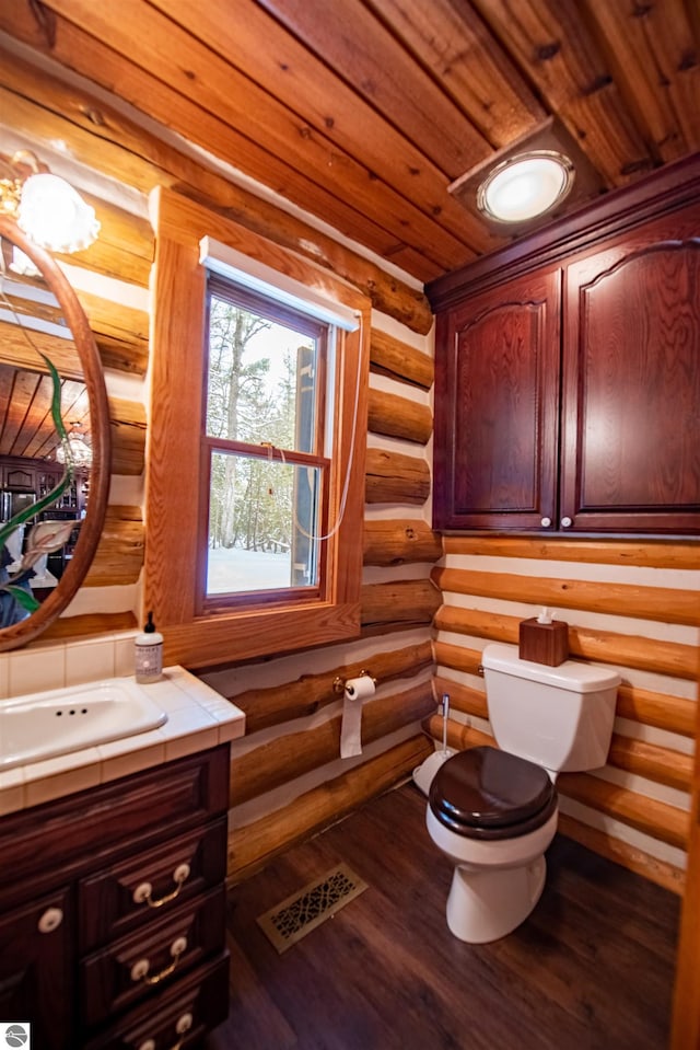 bathroom with hardwood / wood-style floors, rustic walls, wooden ceiling, vanity, and toilet