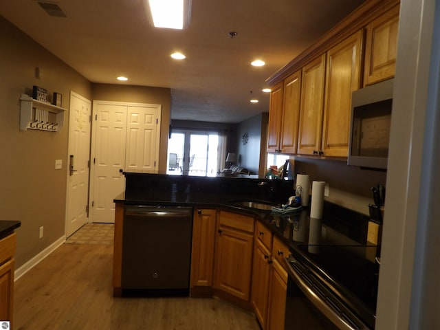 1246 Sunnyside Dr Unit 304Week 8, Cadillac, MI 49601 - kitchen with dishwasher, a peninsula, stainless steel microwave, dark countertops, and brown cabinets