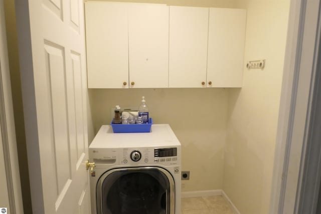 clothes washing area with cabinets, light tile patterned floors, and washer / dryer