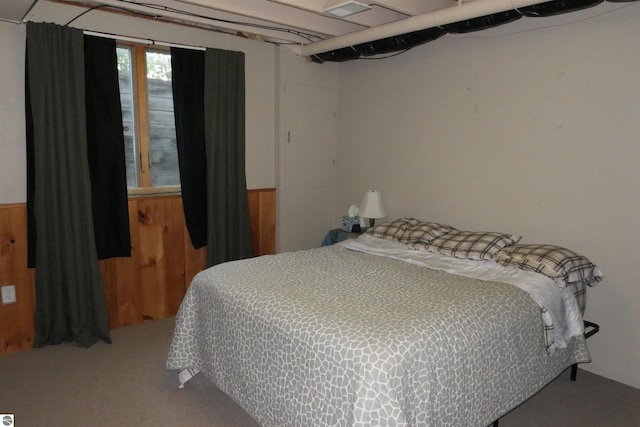 carpeted bedroom featuring wooden walls