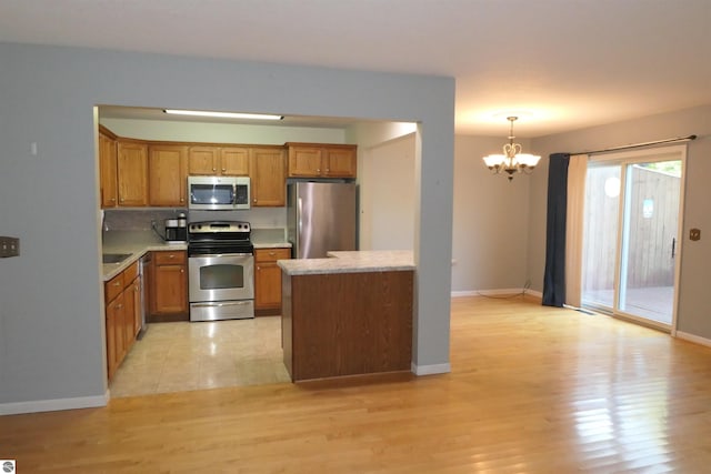 kitchen featuring backsplash, stainless steel appliances, light wood-type flooring, decorative light fixtures, and a notable chandelier