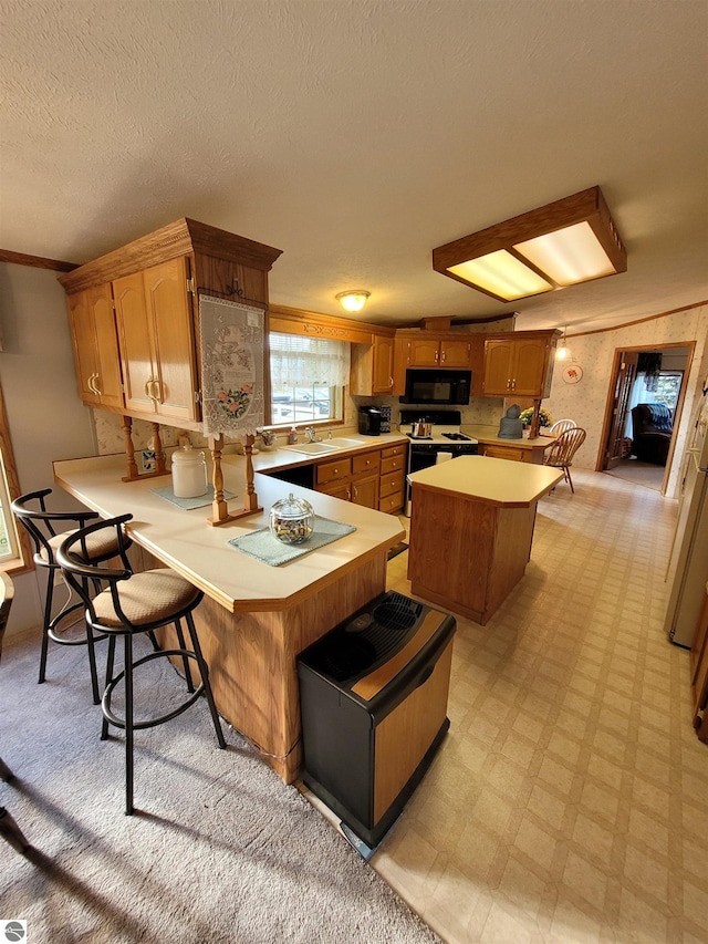 kitchen with a textured ceiling, white range, kitchen peninsula, and a breakfast bar area