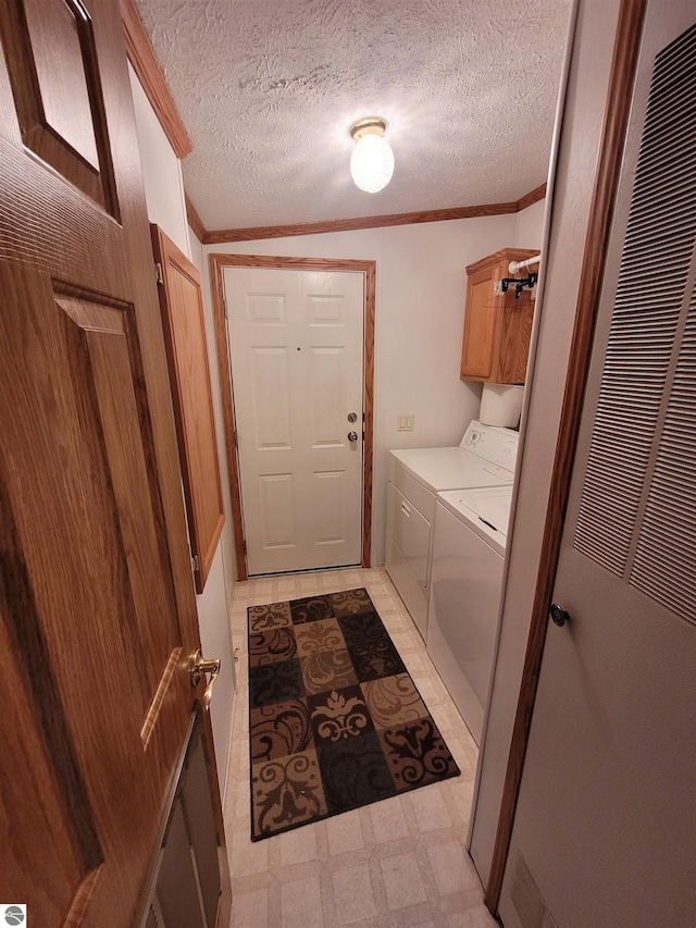 clothes washing area with ornamental molding, cabinets, independent washer and dryer, and a textured ceiling