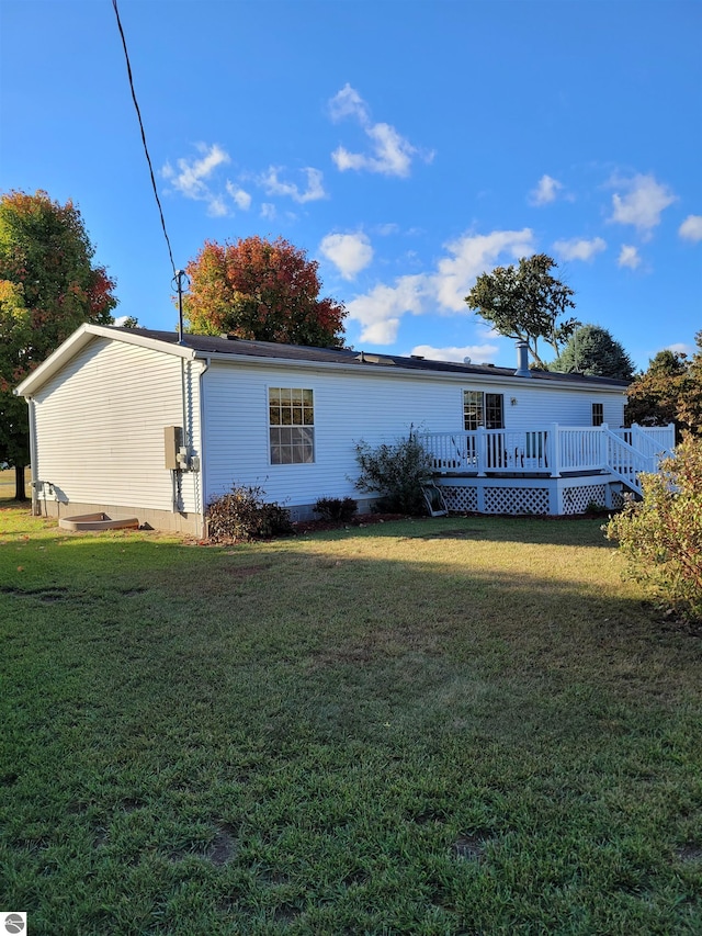 rear view of house featuring a deck and a yard