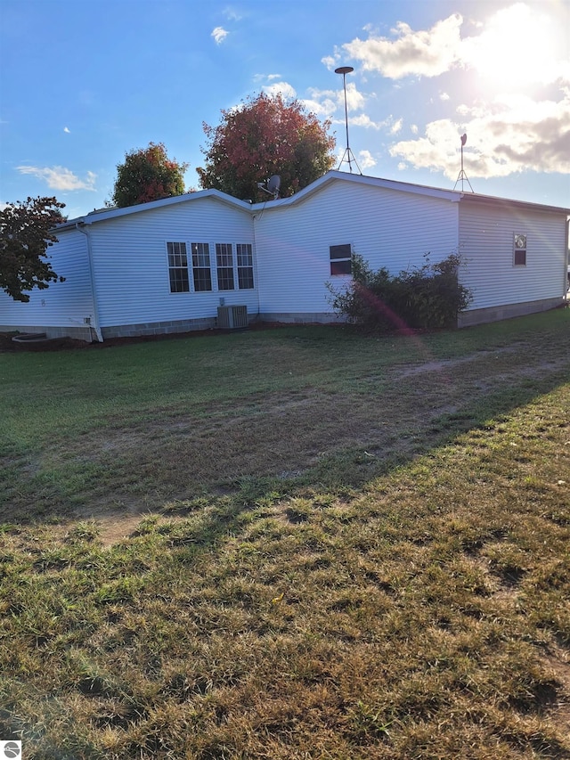 back of property featuring a yard and central AC