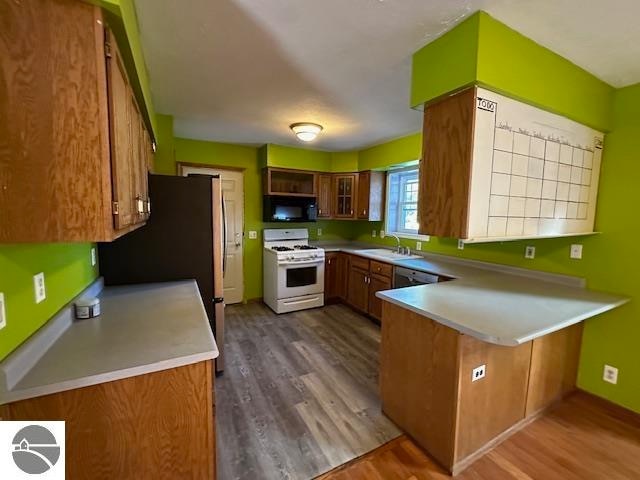 kitchen featuring sink, hardwood / wood-style floors, white gas stove, and kitchen peninsula