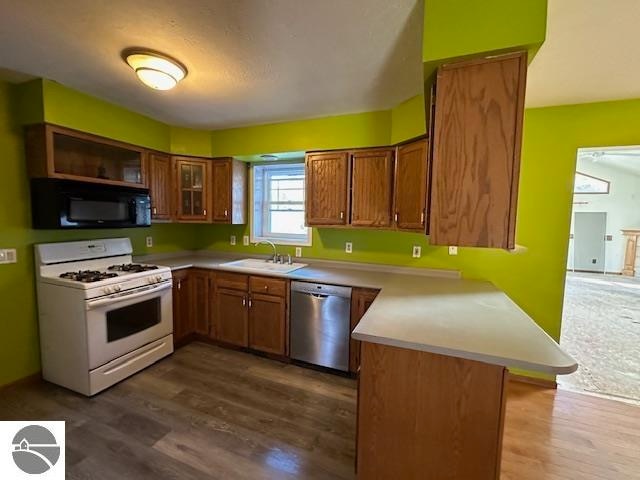 kitchen featuring gas range gas stove, sink, kitchen peninsula, dark hardwood / wood-style flooring, and stainless steel dishwasher