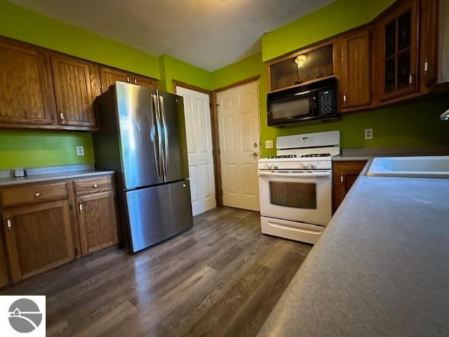 kitchen with stainless steel refrigerator, dark hardwood / wood-style floors, sink, and white gas range oven